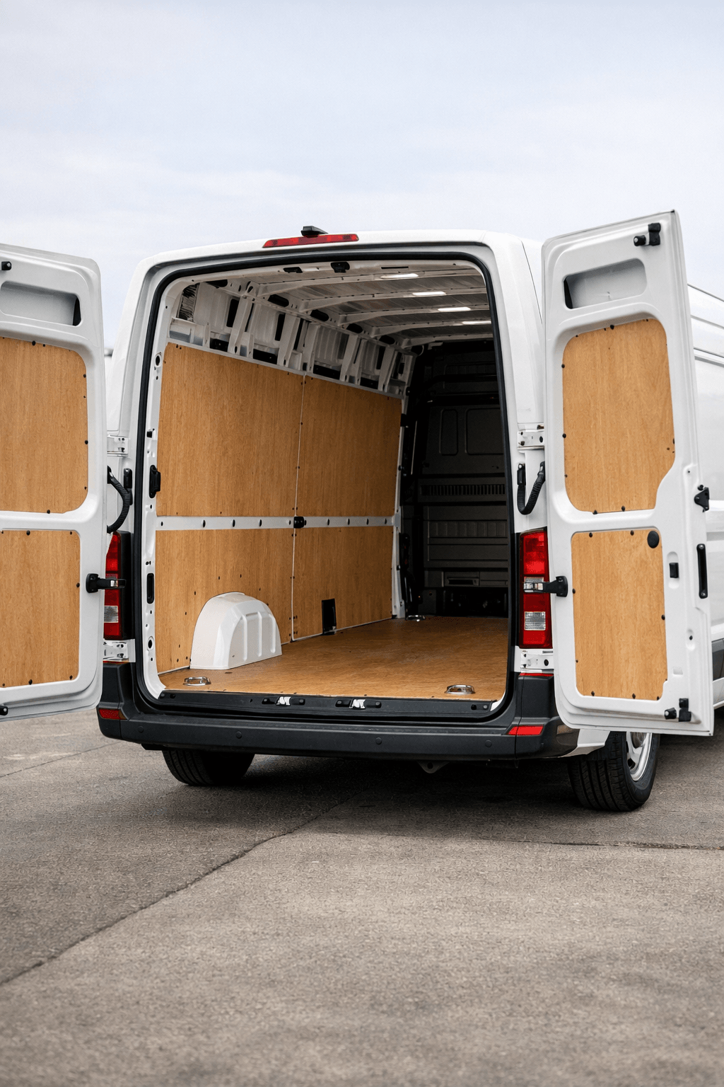 Rear view of a large white panel van with barn doors open at 270 degrees, showing a ply-lined load bay interior with floor lashing rings